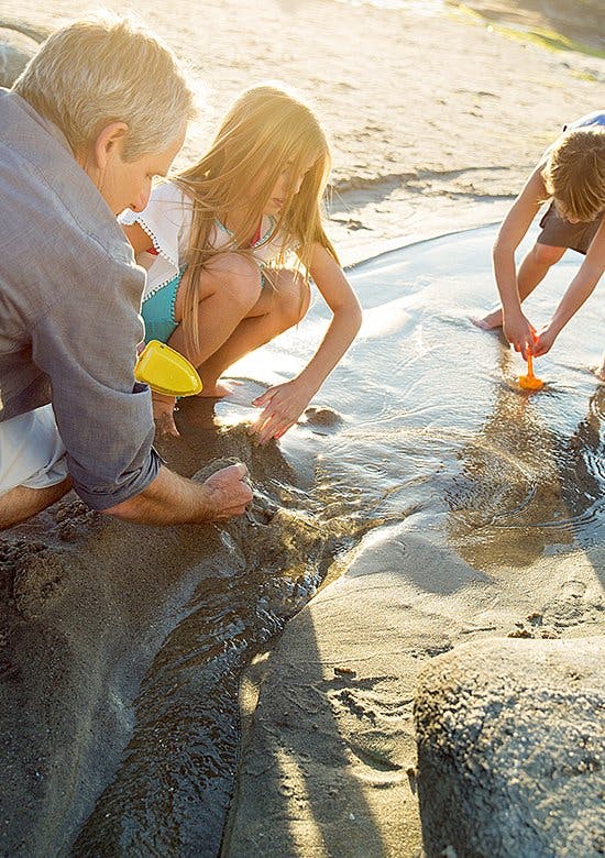 Odkryj radość płynącą z ruchu Odkryj radość płynącą z ruchu - ojciec z dziećmi bawią się łopatkami na plaży