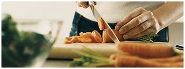 Woman cutting up carrots on wooden cutting boards Woman cutting up carrots on wooden cutting boards