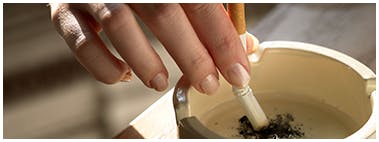 Someone putting out a cigarette in an ashtray Someone putting out a cigarette in an ashtray